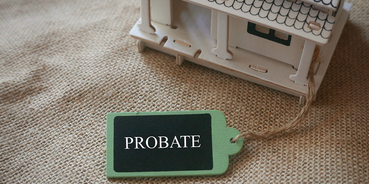 A toy wooden house on a rugs with a wooden tag written with word Probate.