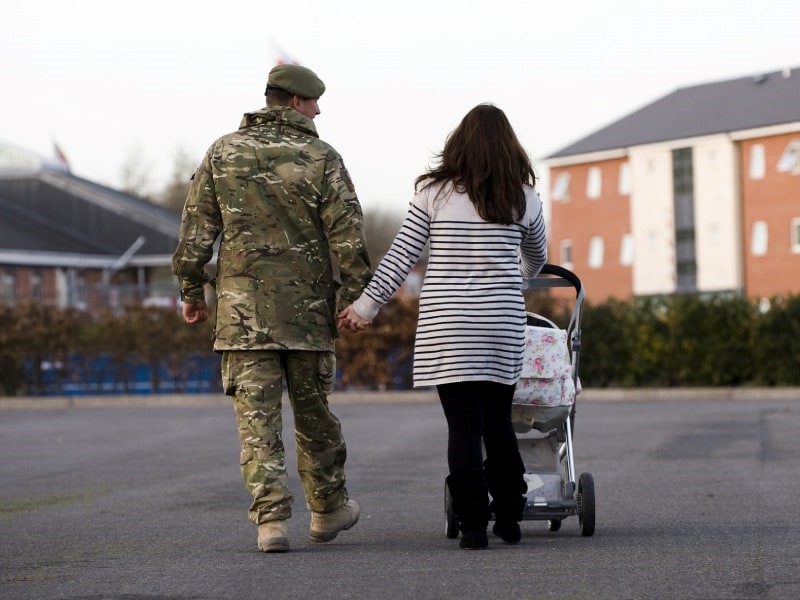 Armed forces personnel walking with partner and buggy