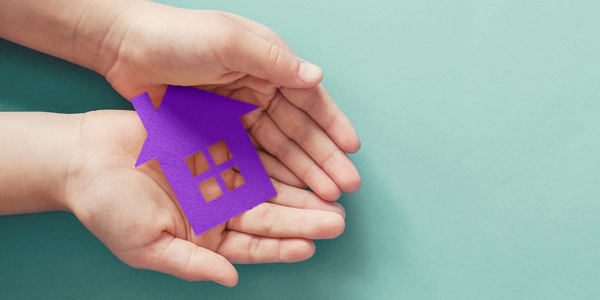 pair of hands with a card cutout of a house in them