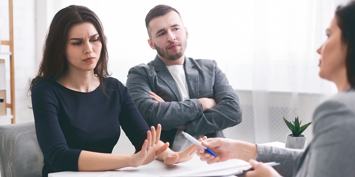 man and woman sitting at table, unhappy with Landlord sitting opposite them